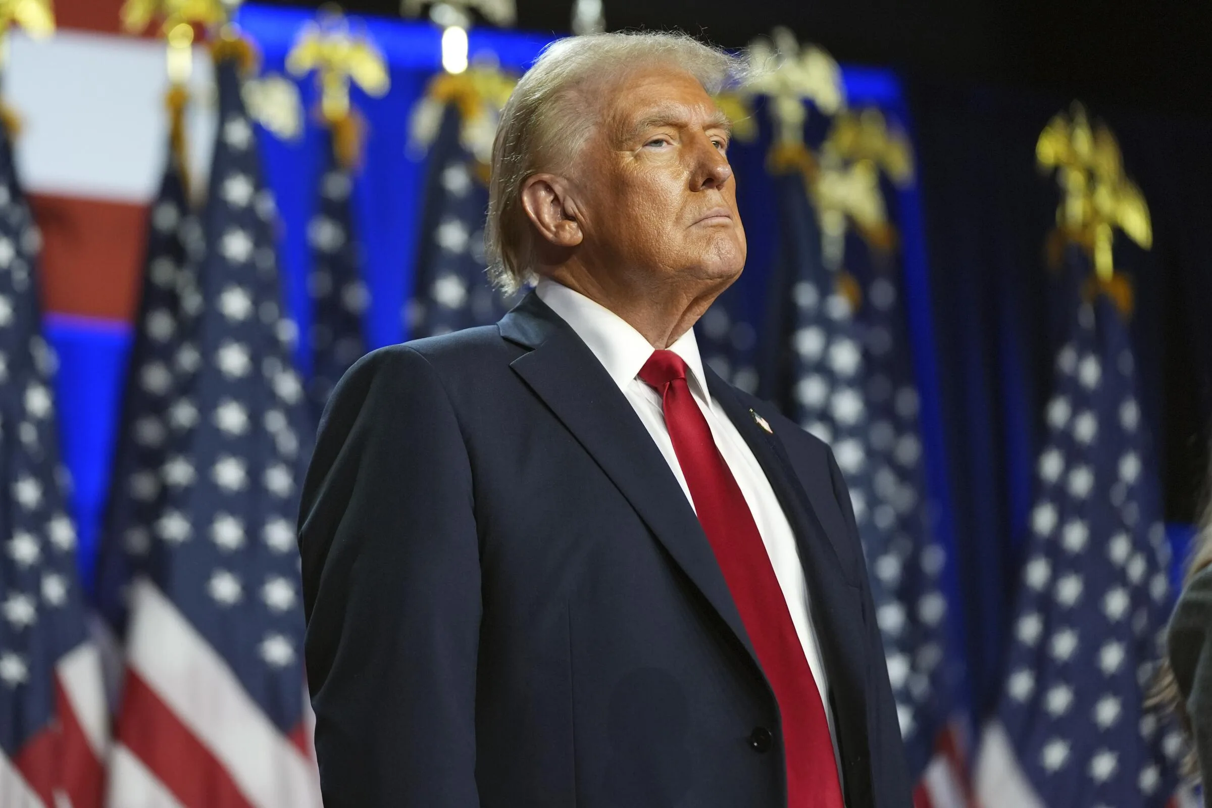 Donald Trump en un evento con banderas de fondo, imagen del artículo sobre aranceles